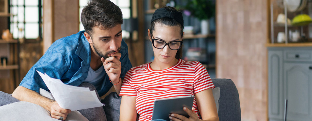 Male and female couple looking at paperwork and iPad