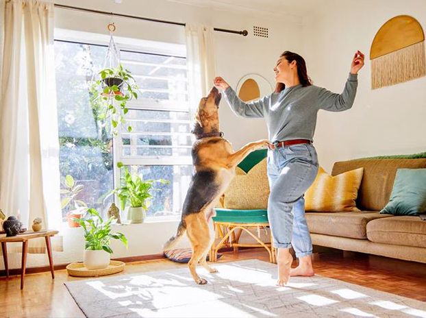 Female home owner happily playing with dog