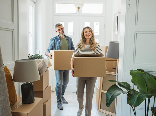 Couple moving into a new home carrying boxes